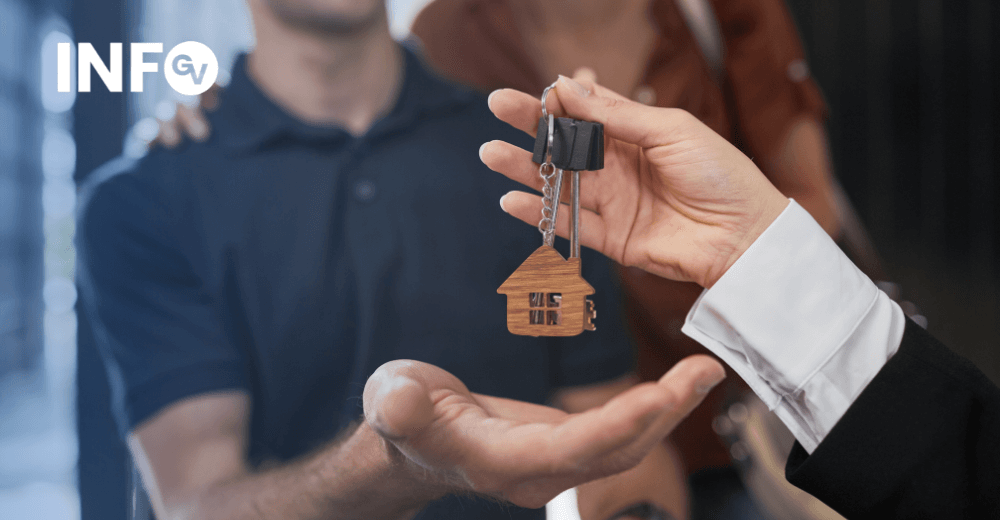 Pessoa a entregar uma chave com porta-chaves em forma de casa a um casal, representando a compra de um imóvel